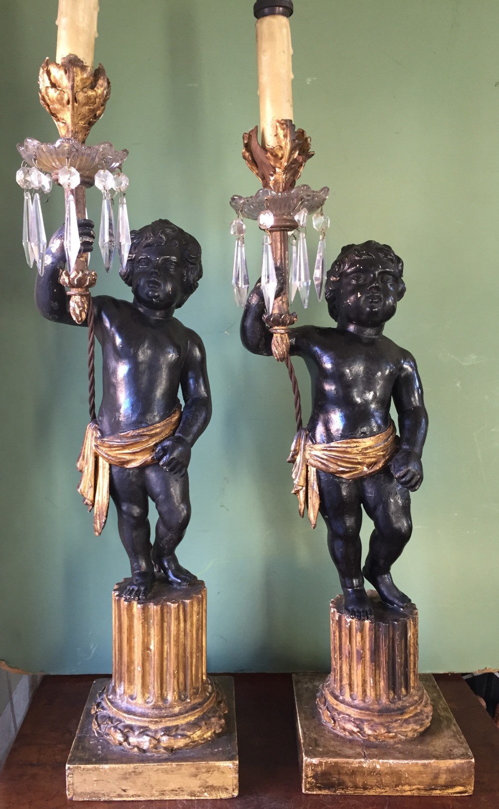 pair of early c19th italian carved wood amorini or cherubs modelled as lamps raised on truncated fluted column bases