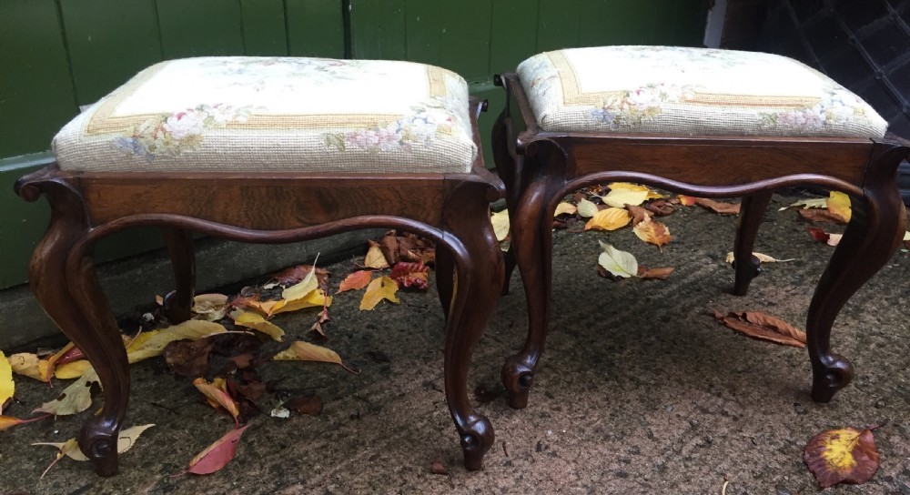 pair of mid c19th victorian period carved and figured rosewoodframed stools with needlework seats