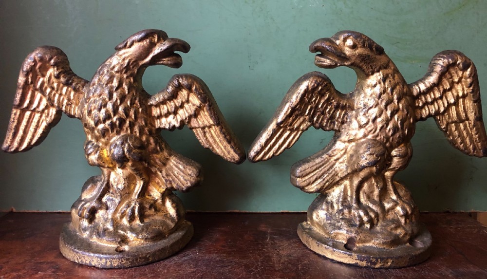pair of early c19th gilded castiron doorstops or porters modelled as opposing eagles