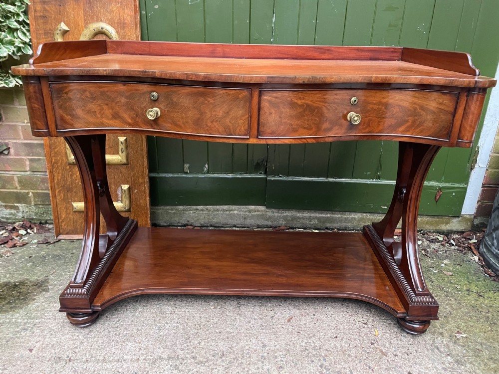 high quality early c19th mahogany serpentinefronted table with threequarter gallery surround top