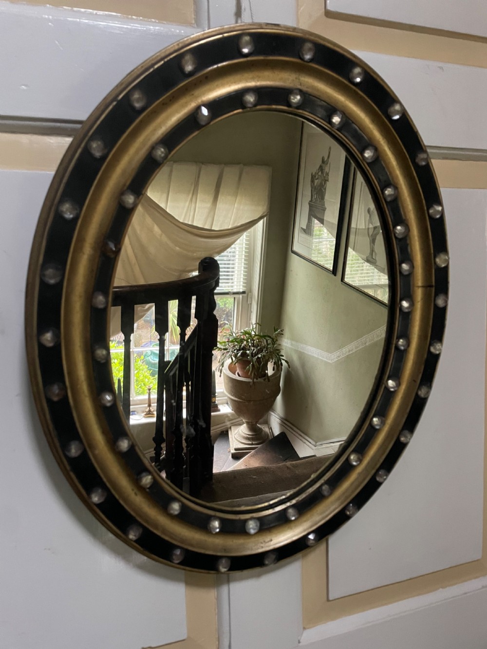 mid c19th irish oval mirror in ebonised and parcelgilt moulded profile frame set with a double band of facetted cutglass cabochons